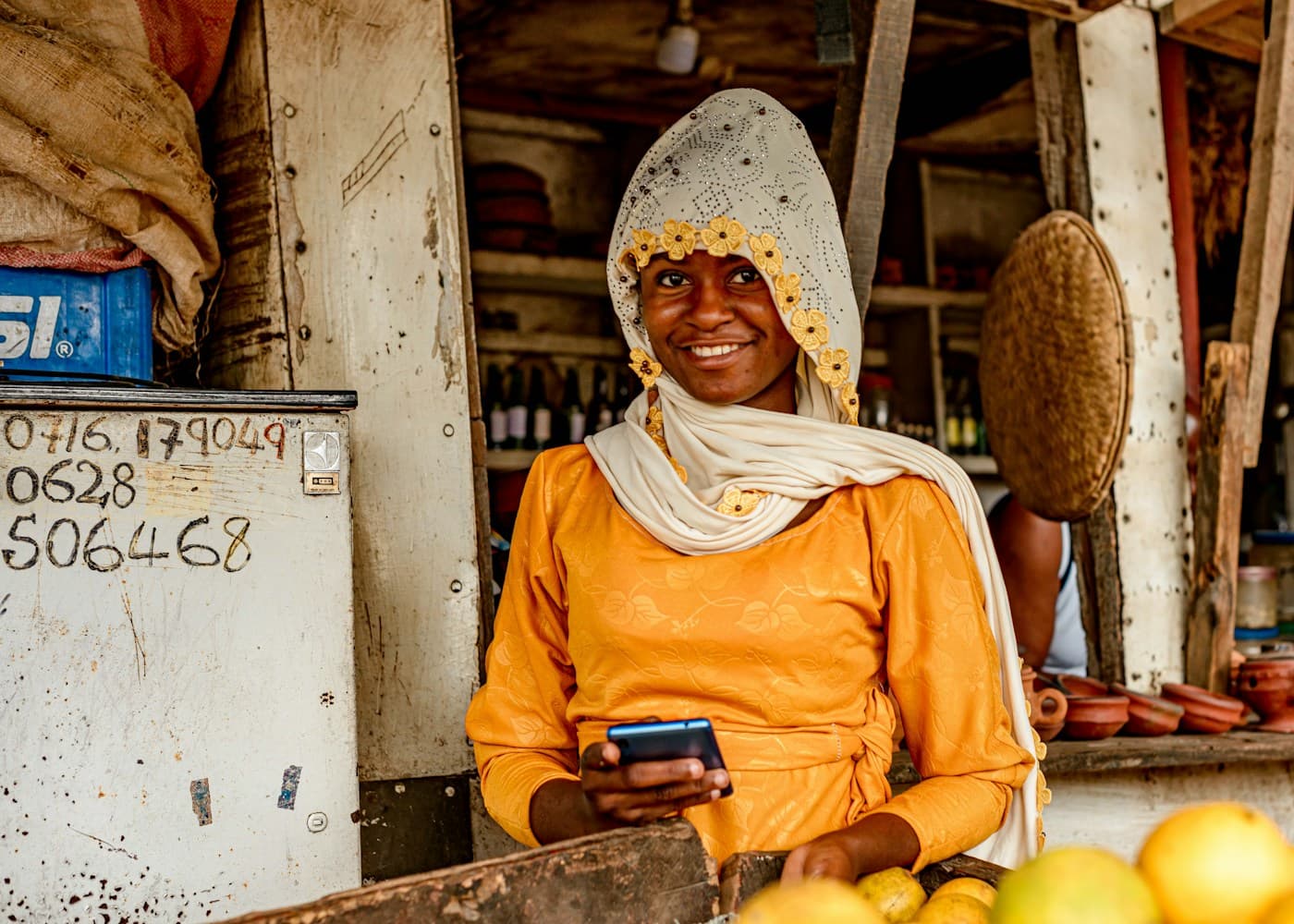 A smiling woman at her stall holding a phone